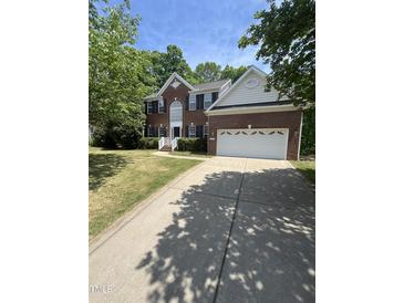 Traditional two-story red brick home with an attached two-car garage and manicured lawn at 205 Quarryrock Rd, Holly Springs, NC 27540