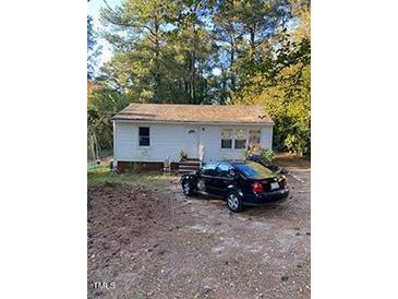 Charming single-story home featuring a classic white exterior, surrounded by mature trees, with a parked car at 724 Oak Rd, Raleigh, NC 27603