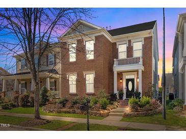 Charming two-story brick home with a small front balcony and manicured landscaping at twilight at 805 Historian St, Raleigh, NC 27603