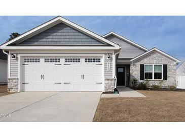 Attached two car garage with white door and stone veneer base on a home with gray siding at 8630 Kenridge Ln, Fuquay Varina, NC 27526