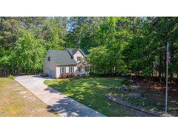 Charming home featuring lush landscaping, a well-maintained lawn, and an American flag waving in the yard at 902 Loop Rd, Clayton, NC 27527