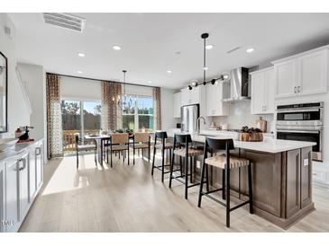 Open-concept kitchen with white cabinets, stainless steel appliances, and a dining area with natural light at 10006 Secluded Garden Drive Rd # 181, Apex, NC 27523