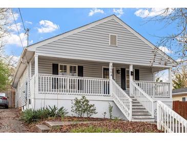 Charming home featuring gray siding, black shutters, a welcoming porch, and well-maintained landscaping at 1304 Drew St, Durham, NC 27701