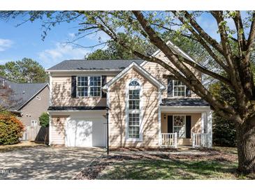 Charming two-story home features a manicured lawn, attached garage, and a welcoming front porch with decorative wreath at 209 Tullich Way, Holly Springs, NC 27540