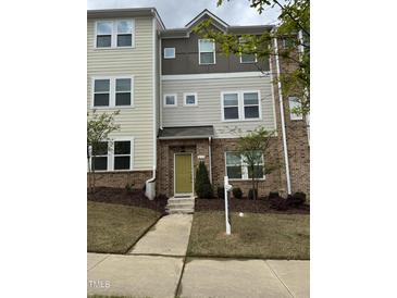 Inviting townhome featuring a mix of brick and siding, with a neatly landscaped front yard and a bright, welcoming entrance at 219 Adobe Pl, Cary, NC 27519