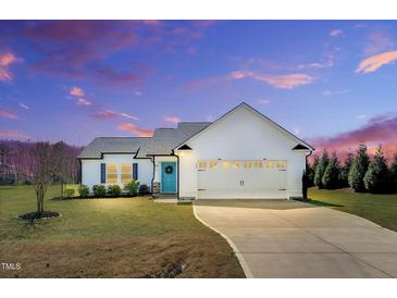 Beautiful, white single-story home with a large garage and a well-manicured lawn underneath a dramatic sky at 28 Sandcastle Ln, Four Oaks, NC 27524