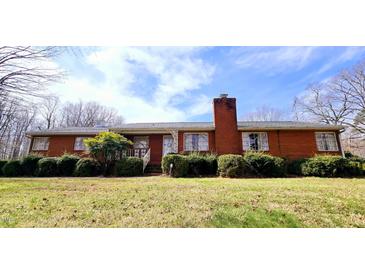 Charming red brick home featuring mature landscaping, a brick chimney, and a well-manicured front yard at 3015 Nc Hwy 87 South, Graham, NC 27253