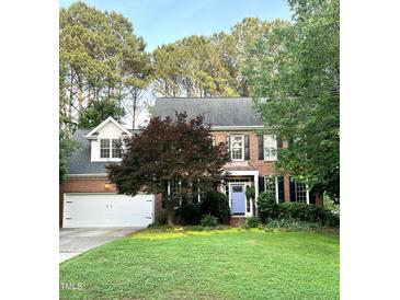 Charming two-story brick home featuring a manicured lawn, lush trees and a delightful periwinkle front door at 307 Kellyridge Dr, Apex, NC 27502