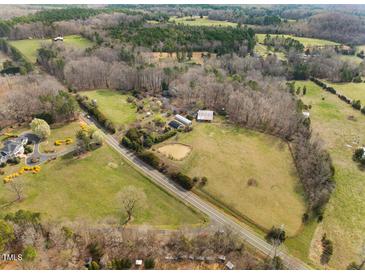 Expansive aerial view of a beautiful lot with mature trees, open pasture and a home at 4811 New Sharon Church Rd, Hillsborough, NC 27278
