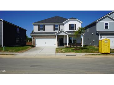 Charming two-story home featuring a two-car garage, partial brickwork, and a well-manicured front yard at 571 White Birch Ln, Angier, NC 27501