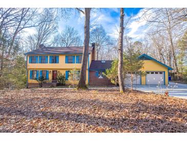 Two-story home with yellow siding, blue shutters, brick accents, and a two-car garage at 94 Cedar Hills Cir, Chapel Hill, NC 27514
