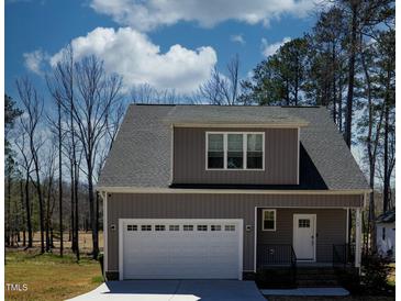Charming home featuring a gray exterior, garage, manicured lawn, and well-maintained landscaping at 169 Black Cloud Dr, Louisburg, NC 27549