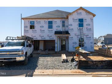 New home under construction featuring Tyvek home wrap, windows, and a truck in the driveway at 18 Thistle Patch Pl, Angier, NC 27501