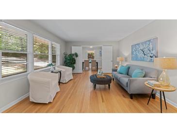 Bright living room with hardwood floors, a gray couch, and large windows that let in natural light at 3605 Octavia St, Raleigh, NC 27606