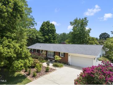 Charming brick home featuring a well-manicured lawn, mature trees, and a two-car garage at 401 Fletcher Dr, Raleigh, NC 27603