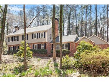 Charming two-story home featuring a brick facade, black shutters, and a well-manicured lawn with mature trees at 609 Brookview Dr, Chapel Hill, NC 27514