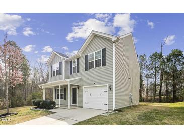 Two-story home showing the side view with gray siding, an attached garage, and a well-manicured lawn at 1536 Ricochet Dr, Raleigh, NC 27610