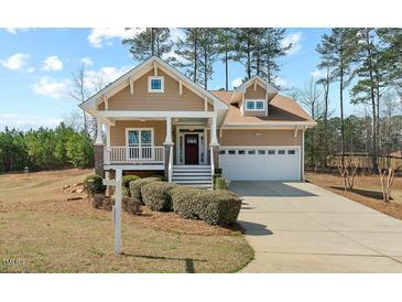 Charming home features a well-manicured lawn, inviting front porch and attached two-car garage at 203 Streamside Dr, Sanford, NC 27330