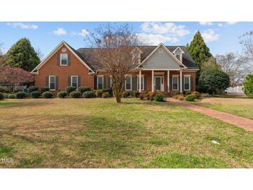 Charming brick home with a well-manicured lawn, complemented by colorful landscaping at 205 Parliament Pl, Dunn, NC 28334