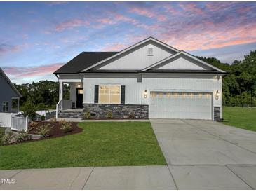 Charming single-Gathering home showcasing a well-manicured lawn, two car garage, and stone accents at 228 Pecan Valley Way, Four Oaks, NC 27524
