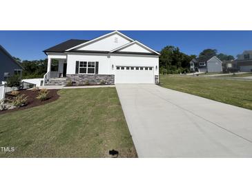 Charming two-story home with manicured lawn, gray stone accents, and a spacious two car garage at 228 Pecan Valley Way, Four Oaks, NC 27524