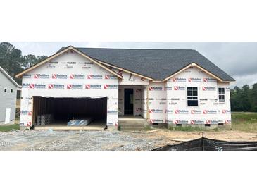 Unfinished exterior of a one story home showing construction wrap, window and door openings, and an attached two car garage at 79 Tee Time Ter, Benson, NC 27504