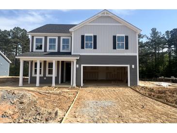 Two-story home featuring gray siding, white trim, covered porch, and an attached two car garage at 98 Tee Time Ter, Benson, NC 27504