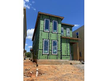 Unfinished two-story home with visible frame and windows under a blue sky, showcasing the construction phase at 107 Parkland Dr, Pittsboro, NC 27312