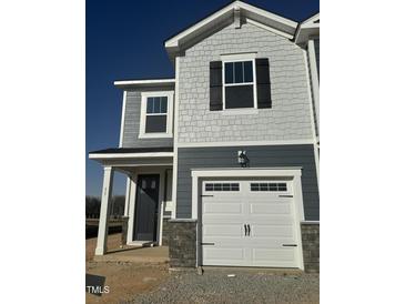 New construction home with gray siding, white garage door, and stone accents on the lower level at 11 Silver Pne Dr, Angier, NC 27501