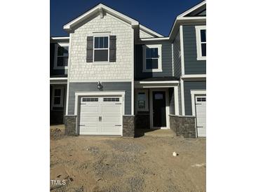Charming townhome featuring a white garage door, stone accents, and a mix of shingle and horizontal siding at 17 Silver Pne Dr, Angier, NC 27501