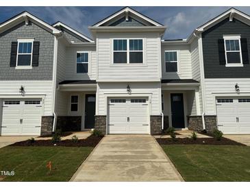 New townhomes featuring attached garages, black shutters, and light-colored siding, creating a modern and appealing facade at 18 Twin Birch Dr, Angier, NC 27501