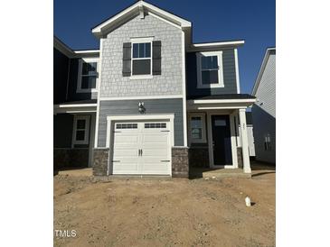 New two story home with gray siding, white garage door, and an inviting front porch at 25 Silver Pne Dr, Angier, NC 27501