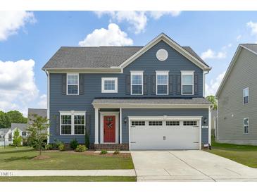 Charming two-story home with blue siding, a red front door, and a white two-car garage at 2801 Landon Ridge Dr, New Hill, NC 27562