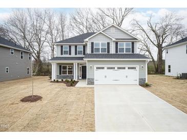 Two-story home with gray siding, black shutters, and a two-car garage on a lawn with dormant grass at 316 Hopewell Branch Ct, Smithfield, NC 27577