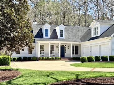 Charming home featuring a manicured lawn, two-car garage, and inviting front porch with rocking chairs at 321 Nottingham Dr, Chapel Hill, NC 27517
