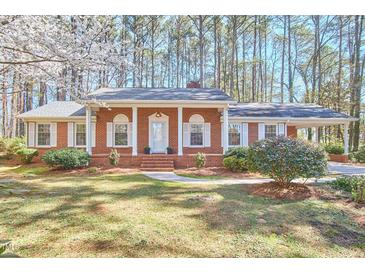 Charming red brick home with white shutters, portico and blossoming tree in landscaped front yard at 3613 Hope Valley Rd, Durham, NC 27707