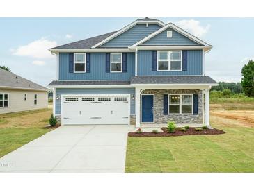 Two-story home featuring blue siding, a white garage door, stone accents, and a well-manicured lawn at 396 Hopewell Branch Ct, Smithfield, NC 27577