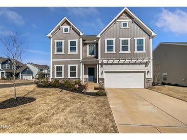 Inviting two-story home featuring a two-car garage, blue door, and a meticulously maintained landscaped front yard at 7331 Livestock Rd, Mebane, NC 27302
