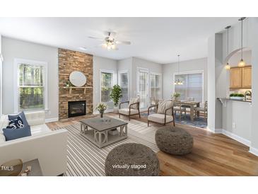 Bright living room with a stone fireplace, hardwood floors, and lots of natural light at 1100 Dotson Way, Apex, NC 27523