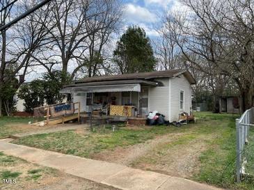 Modest single-story home featuring a covered porch and ramp amidst a spacious, tree-lined yard at 406 S Flanner St, Burlington, NC 27215