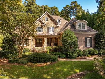 Charming stone and brick home with a well-manicured front yard and mature trees at 1616 Kirkby Ln, Raleigh, NC 27614