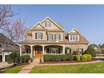 Stunning brick home with a welcoming front porch, manicured landscaping, and classic architectural details at 321 Weycroft Grant Dr, Cary, NC 27519