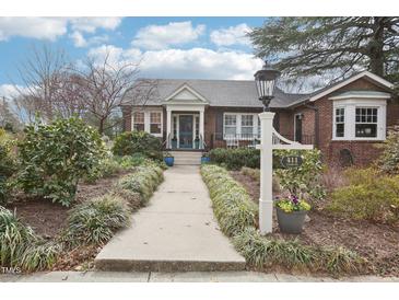 Charming brick home with a landscaped front yard and walkway leading to a teal blue front door at 411 Circle Dr, Burlington, NC 27215
