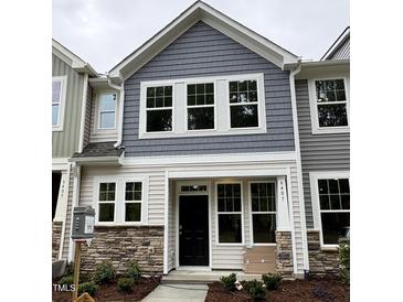 Charming two-story townhome featuring stone accents, neutral siding, and a covered front porch at 6407 Granite Quarry Dr, Raleigh, NC 27610