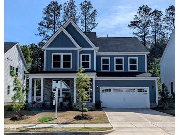 Beautiful two-story home featuring blue siding, stone accents, a welcoming front porch, and a two-car garage at 724 Red Arrow Dr, Knightdale, NC 27545