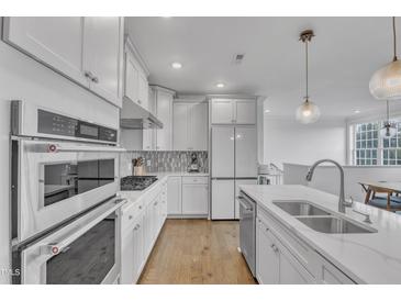 Bright kitchen with white cabinets, stainless steel appliances, and modern pendant lighting at 10210 Sablewood Drive # 112, Raleigh, NC 27617