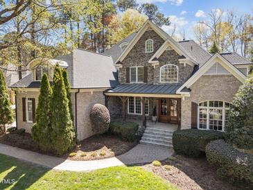 Beautiful stone and brick home with well-manicured landscaping and a welcoming front porch at 10540 Byrum Woods Dr, Raleigh, NC 27613