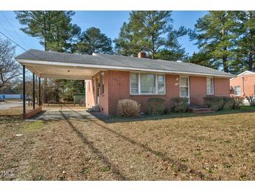 Classic red brick home featuring an attached carport and mature trees in a tranquil neighborhood setting at 1101 Nashville Rd, Rocky Mount, NC 27803