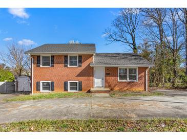 Traditional brick home with black shutters and mature trees under a bright blue sky at 1506 N Mebane St, Burlington, NC 27217