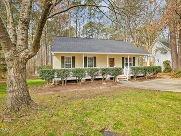 Charming single-story home with yellow siding, green shutters, and a cozy front porch at 204 Sugarland Dr, Apex, NC 27502